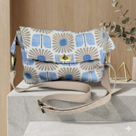 Floral patterned handbag with beige strap on a light surface